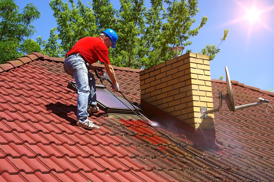 Man pressure cleaning to remove moss from a roof
